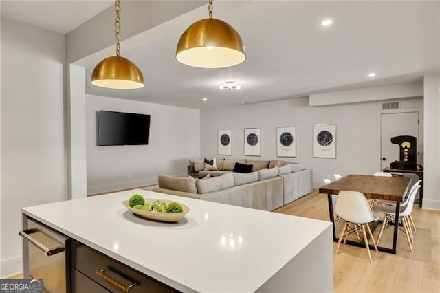kitchen featuring pendant lighting, light countertops, light wood-type flooring, and visible vents