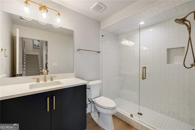 bathroom featuring toilet, wood finished floors, a stall shower, visible vents, and vanity