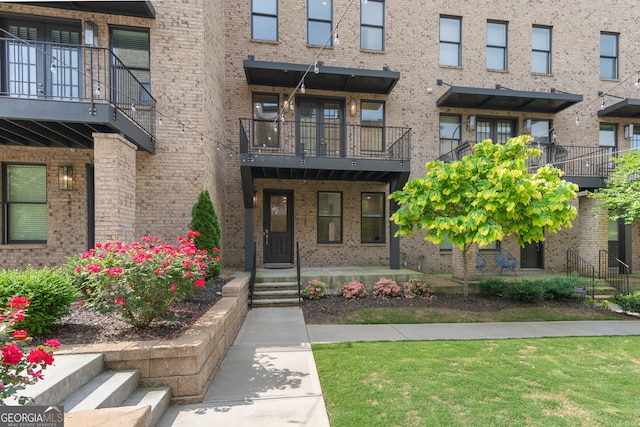 property entrance featuring a balcony and brick siding