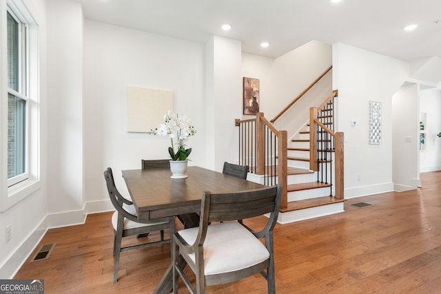dining space with visible vents, light wood-style floors, baseboards, and stairway