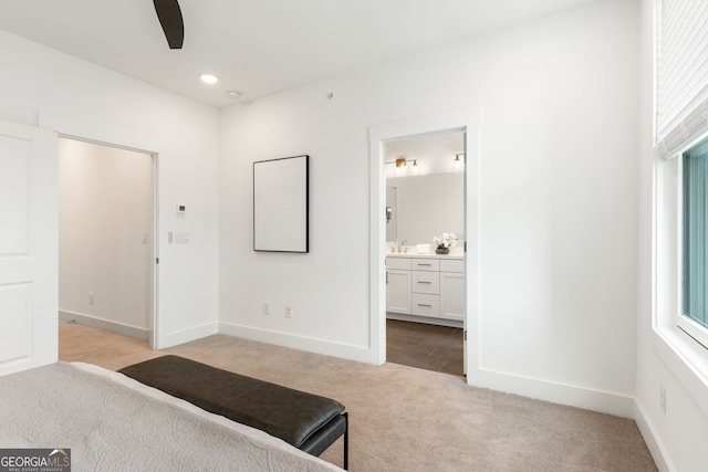 carpeted bedroom with baseboards, recessed lighting, connected bathroom, and a sink