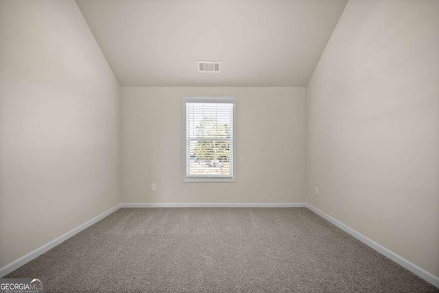 carpeted spare room with visible vents, baseboards, and vaulted ceiling