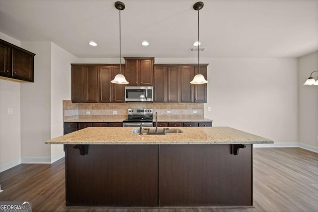 kitchen with backsplash, baseboards, appliances with stainless steel finishes, and a sink