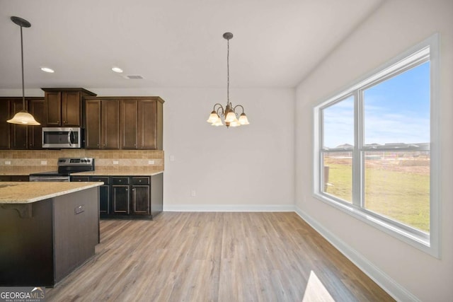 kitchen featuring stainless steel appliances, baseboards, and light wood finished floors