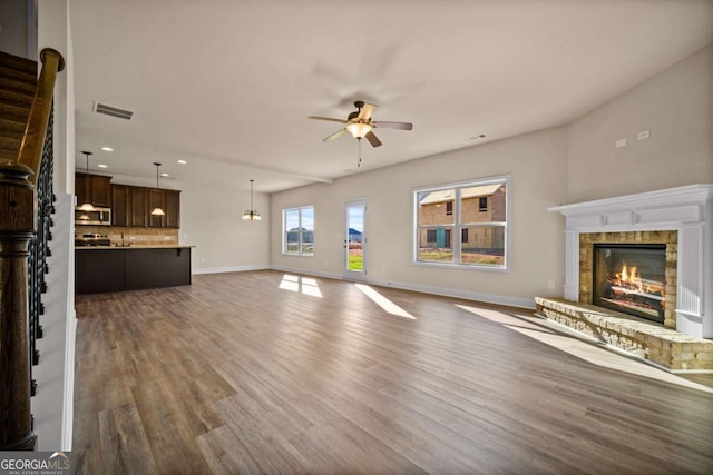 unfurnished living room featuring a ceiling fan, dark wood-style flooring, a brick fireplace, baseboards, and recessed lighting