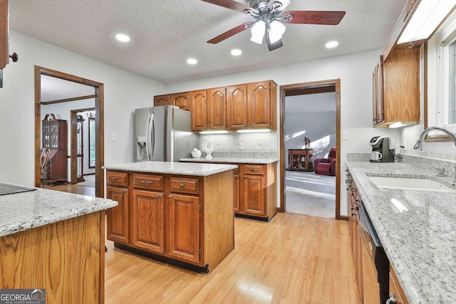 337 Andrew Bailey Rd, Sharpsburg, GA 30277 - kitchen featuring stainless steel fridge, light wood finished floors, brown cabinetry, a ceiling fan, and a textured ceiling