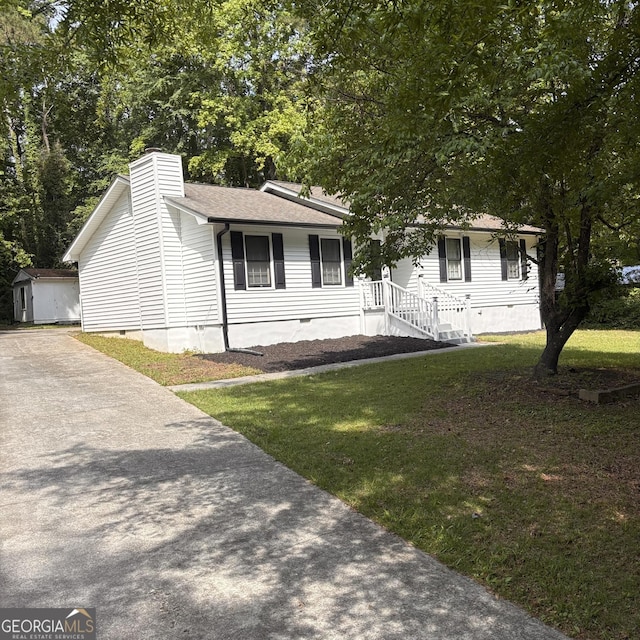 view of front of property with a shed, a front yard, crawl space, an outbuilding, and a chimney