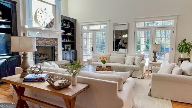 living room featuring wood finished floors, a stone fireplace, and a towering ceiling
