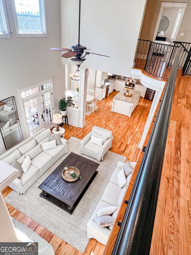 living area with ceiling fan, light wood finished floors, and a high ceiling
