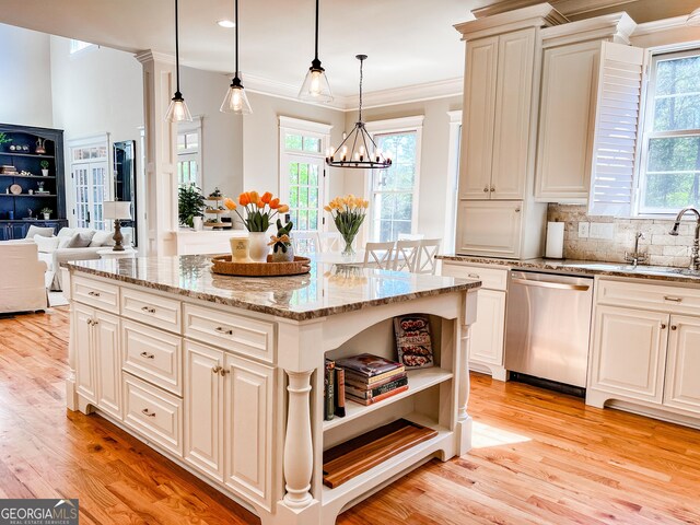 kitchen with stainless steel dishwasher, light stone countertops, plenty of natural light, and light wood finished floors