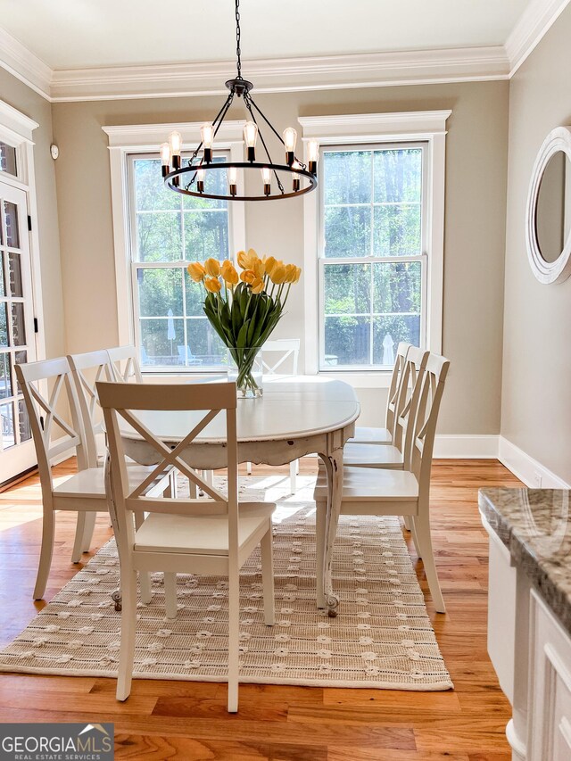 dining room featuring light wood-style floors, baseboards, ornamental molding, and a chandelier