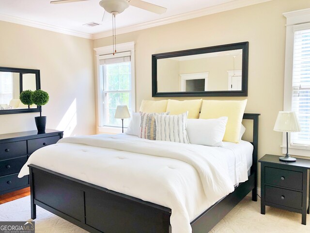 bedroom with visible vents, ornamental molding, a ceiling fan, and multiple windows