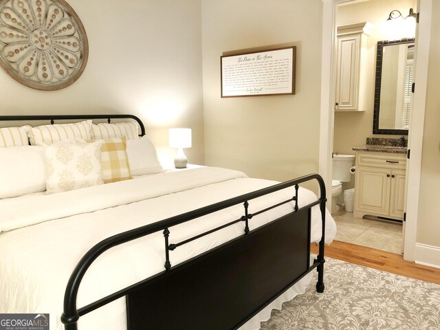 bedroom featuring ensuite bathroom and light wood-style floors