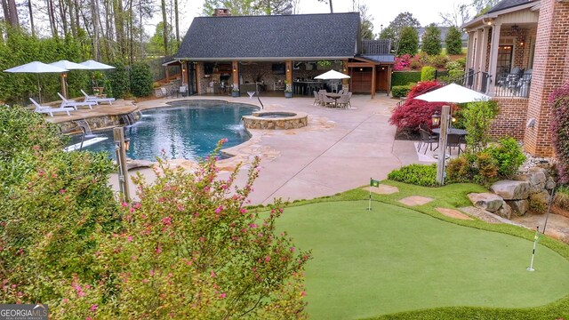 view of swimming pool featuring a pool with connected hot tub, fence, a fire pit, and a patio area