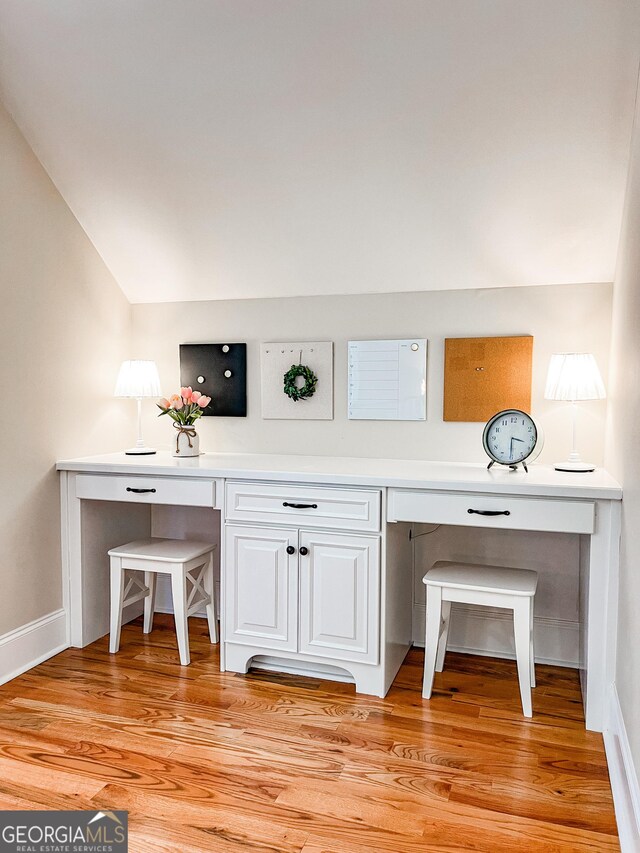 interior details featuring baseboards, built in desk, and wood finished floors