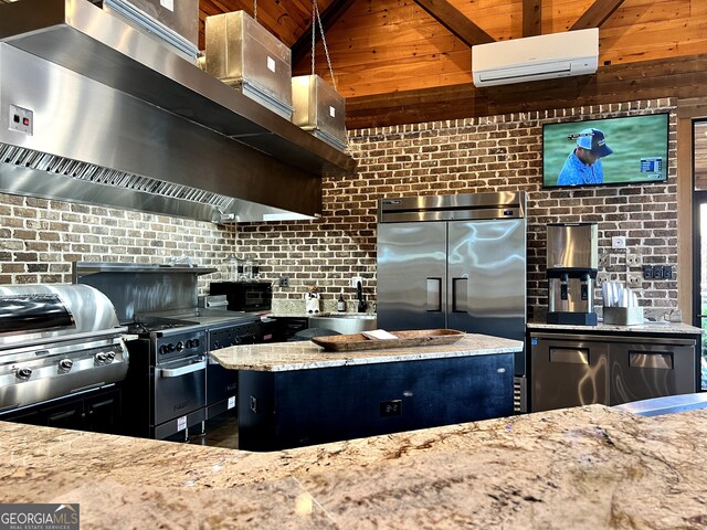 kitchen with light stone countertops, a sink, an AC wall unit, stainless steel built in refrigerator, and wall chimney exhaust hood