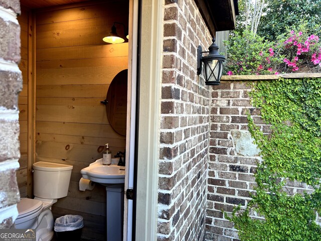 half bathroom featuring toilet and wood walls