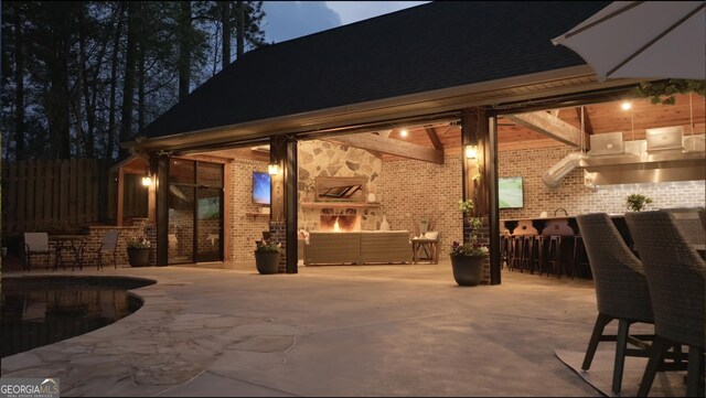 patio at twilight with fence and an outdoor living space with a fireplace