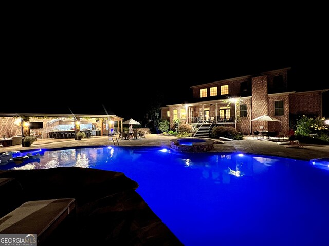 pool at night with stairs, a gazebo, a pool with connected hot tub, and a patio area