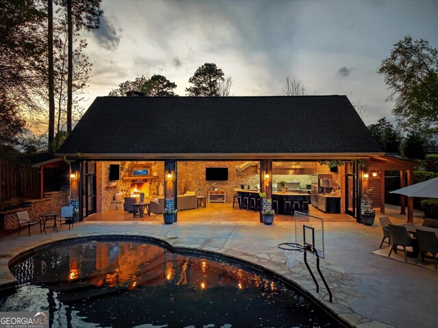 outdoor pool featuring a patio, outdoor dry bar, and a fireplace