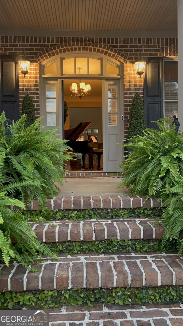 view of exterior entry featuring a porch and brick siding