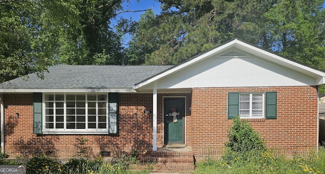 ranch-style home with roof with shingles and brick siding