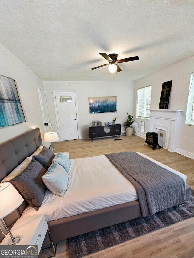 bedroom with baseboards, a textured ceiling, ceiling fan, and wood finished floors