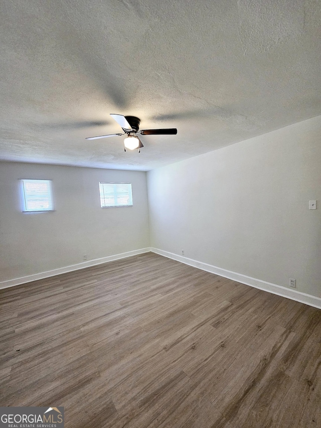spare room with baseboards, a textured ceiling, ceiling fan, and wood finished floors