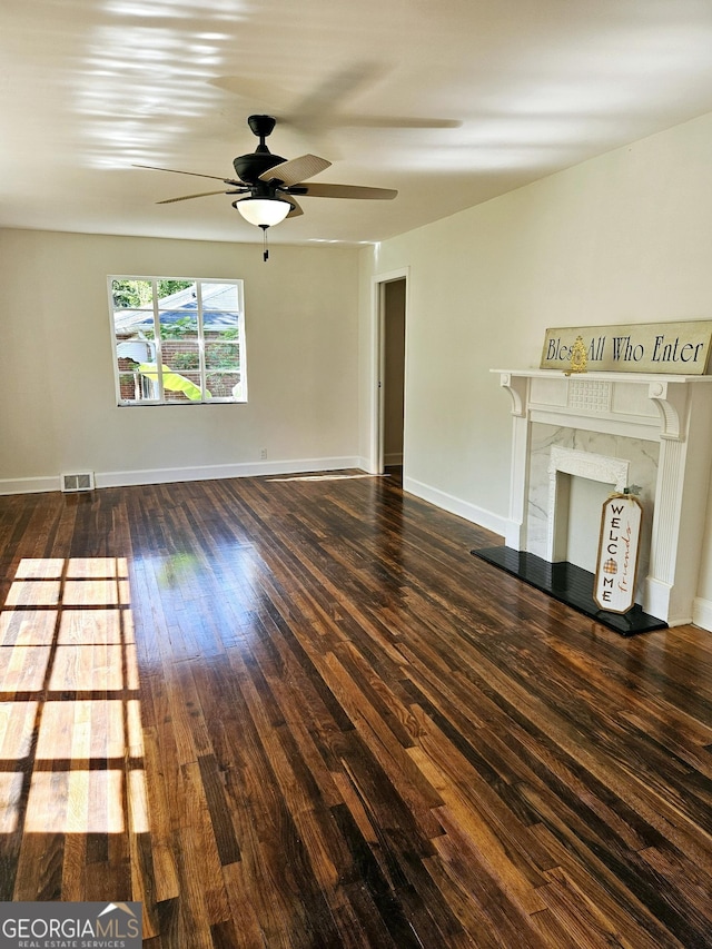 unfurnished living room with ceiling fan, visible vents, hardwood / wood-style flooring, baseboards, and a premium fireplace