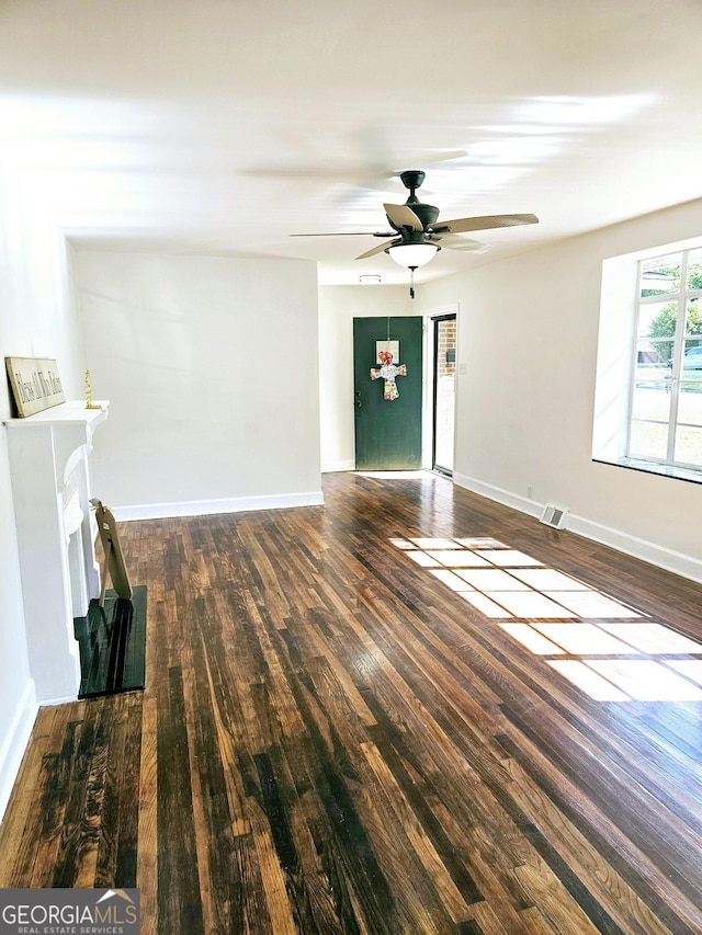 unfurnished living room with baseboards, a ceiling fan, wood finished floors, and visible vents