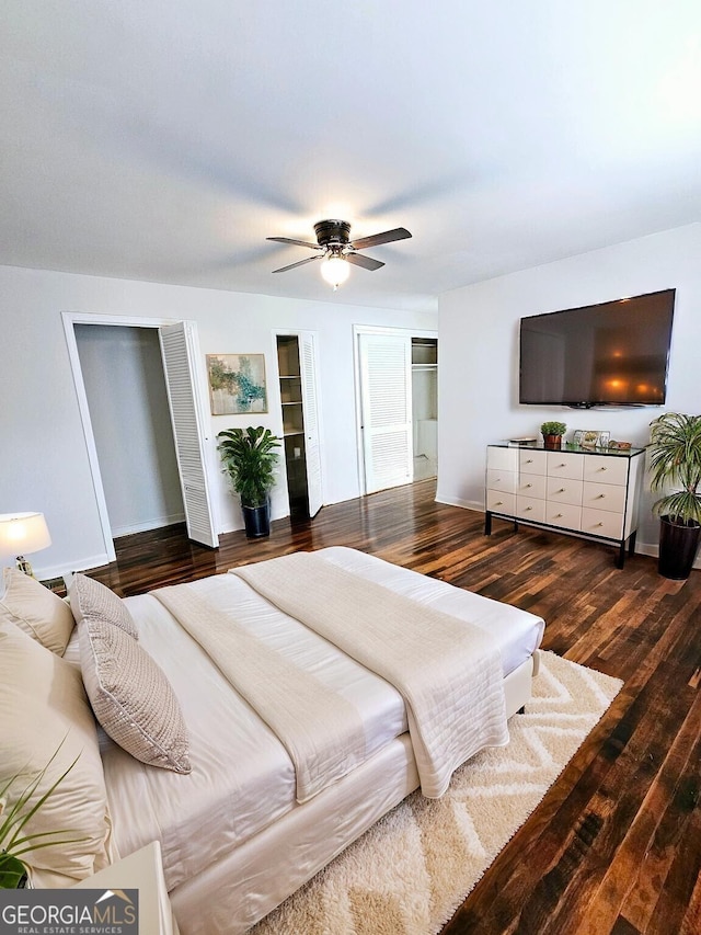 bedroom with a ceiling fan, baseboards, multiple closets, and wood finished floors