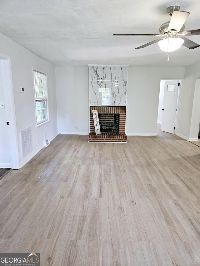 unfurnished living room featuring visible vents, wood finished floors, a fireplace, baseboards, and ceiling fan