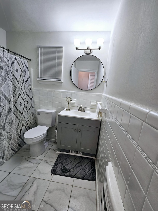 full bathroom featuring toilet, tile walls, a wainscoted wall, and vanity