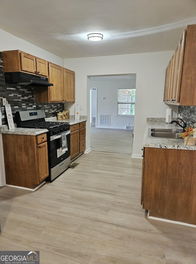 kitchen featuring decorative backsplash, visible vents, a sink, stainless steel gas range, and light wood finished floors