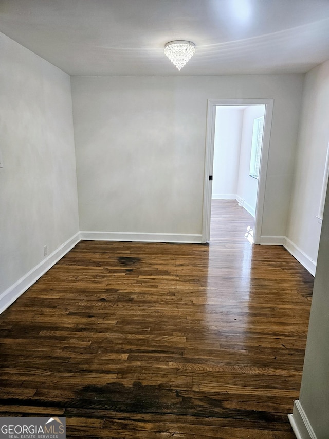 unfurnished room featuring baseboards and dark wood finished floors