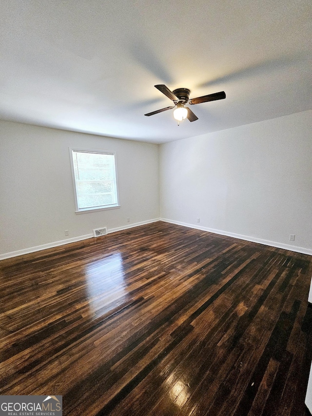 spare room with visible vents, a ceiling fan, dark wood-style flooring, and baseboards