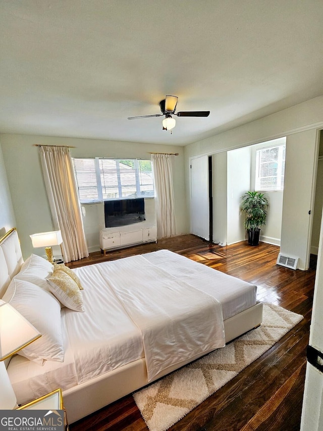 bedroom with ceiling fan, wood finished floors, and visible vents