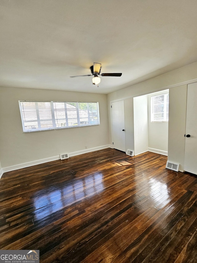 unfurnished room featuring baseboards, a ceiling fan, dark wood-type flooring, and visible vents