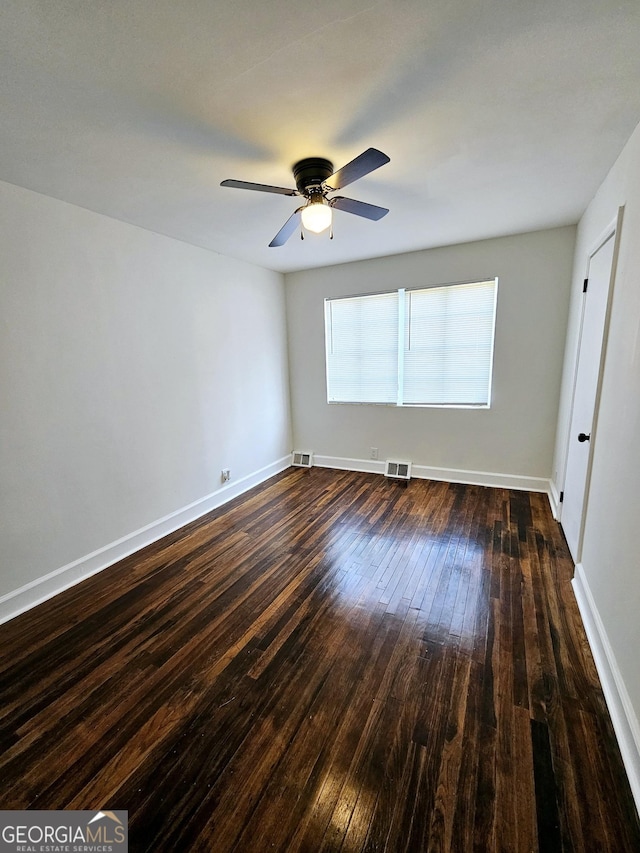 spare room with a ceiling fan, baseboards, visible vents, and dark wood finished floors