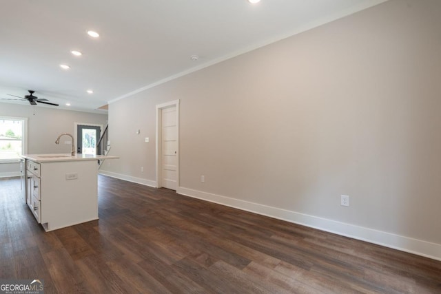 kitchen with recessed lighting, a sink, baseboards, and a kitchen island with sink