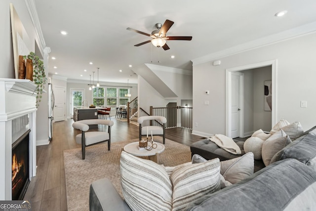 living area featuring dark wood-style flooring, a fireplace, a ceiling fan, recessed lighting, and ornamental molding