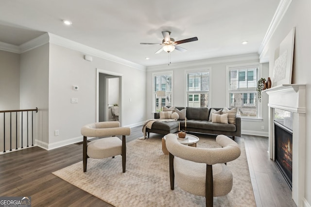 living room featuring baseboards, ornamental molding, a ceiling fan, and dark wood finished floors