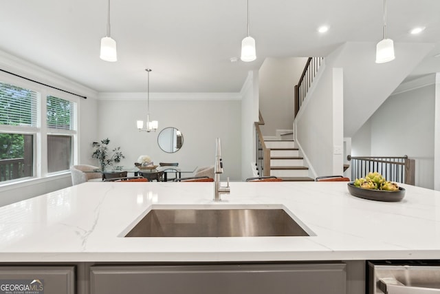 kitchen with decorative light fixtures, crown molding, a sink, light stone counters, and open floor plan