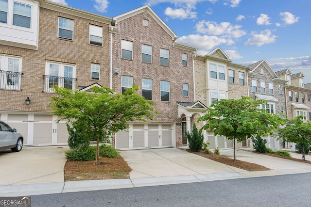 townhome / multi-family property with a residential view, an attached garage, driveway, and brick siding