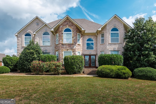 view of front of home with brick siding, a front lawn, and french doors