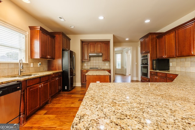 kitchen featuring stainless steel appliances, plenty of natural light, a sink, and tasteful backsplash