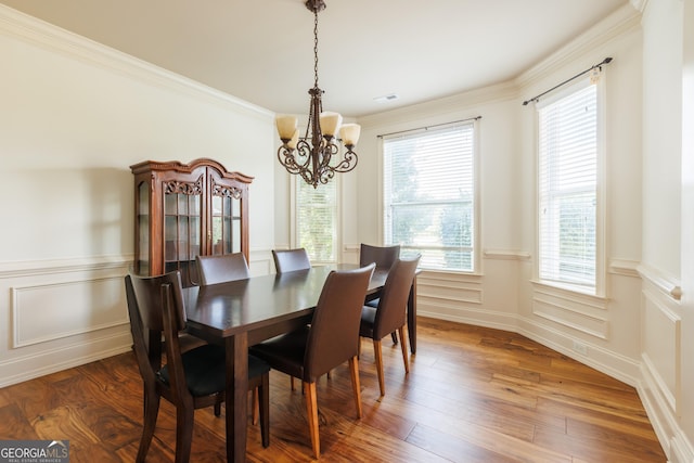 dining area with an inviting chandelier, ornamental molding, a wainscoted wall, and a healthy amount of sunlight