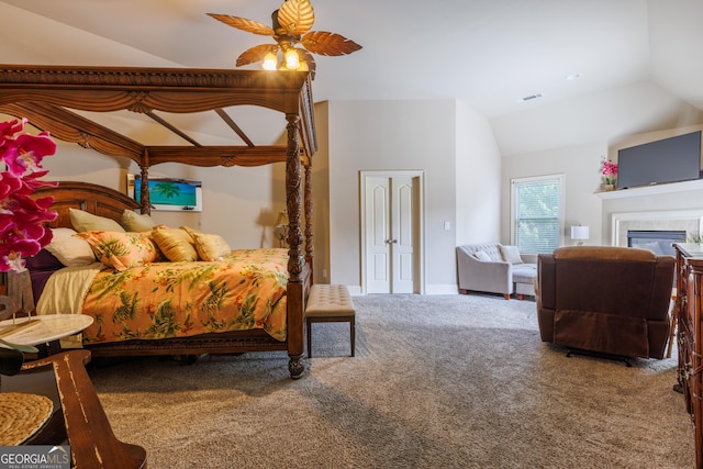 bedroom featuring visible vents, a glass covered fireplace, lofted ceiling, ceiling fan, and carpet