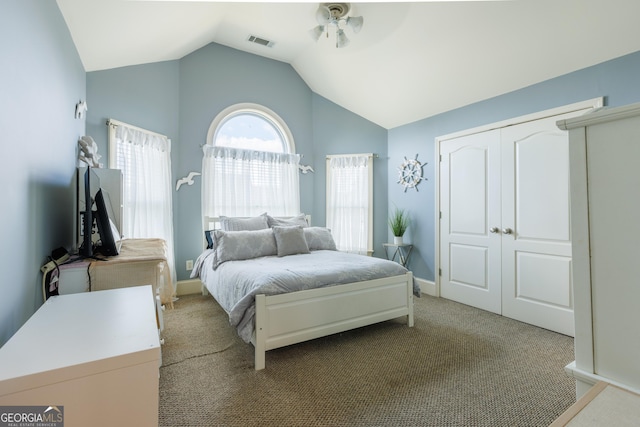 bedroom with visible vents, carpet, lofted ceiling, and a closet