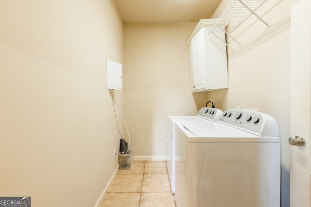 laundry room featuring light tile patterned floors, baseboards, cabinet space, and washing machine and clothes dryer